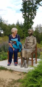 Eine Teilnehmerin nimmt lächelnd neben einer lebensgroßen Bronzestatue Platz.