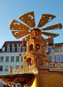 Eine kunstvolle hölzerne Weihnachtspyramide erhebt sich in den blauen Himmel.