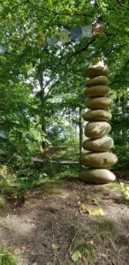 Kunstvoll gestapelte, ovale Steine bilden eine beeindruckende Skulptur im Wald.