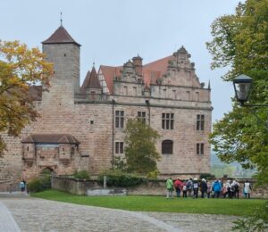 Die Gruppe versammelt sich auf der Rasenfläche vor einem imposanten Sandsteinschloss.