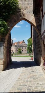 Ein steinerner Torbogen rahmt den Blick auf das dahinterliegende Schlossgebäude.