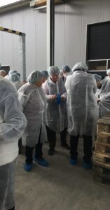 In weißen Schutzanzügen, Hauben und Überschuhen erkundet die Gruppe den Produktionsbetrieb.
