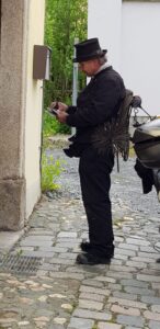 In traditioneller schwarzer Zunftkleidung macht sich der Schornsteinfeger Notizen.