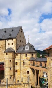 Die wehrhafte Burganlage präsentiert sich mit markanten Ecktürmen unter blauem Himmel.