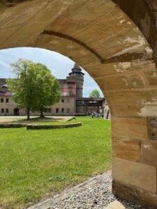 Ein steinerner Torbogen rahmt den Blick auf die grüne Rasenfläche der Burganlage.