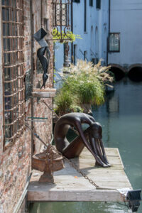 Kunstvolle Bronzefigur auf einem Holzsteg am Wasser