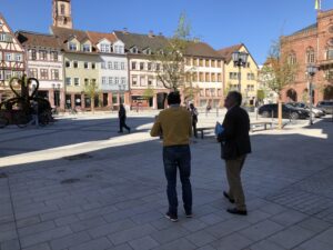 Zwei Männer im Gespräch vor historischer Kulisse