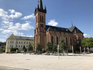 Neugotische Kirche mit spitzem Turm auf offenem Platz