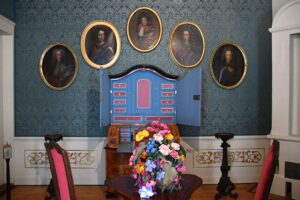 Ein Raum mit Porträts, Gedenkkranz und Ausstellungsstücken