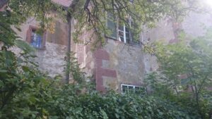 Verwunschener Blick auf ein altes Gebäude hinter Bäumen
