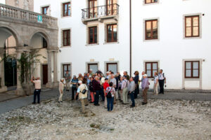 Reisegruppe vor weißer Palastfassade mit Arkaden