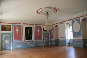 Schlossraum mit farbigen Wandfeldern und Porträts