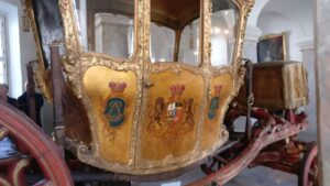 Eine historische Prunkkutsche mit kunstvoll bemalten Seitenflächen und Wappen
