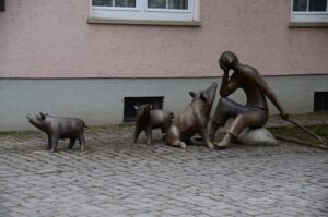Bronzene Figurengruppe mit einer Frau und mehreren kleinen Schweinen