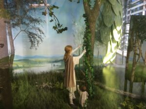 Figurengruppe vor idyllischer Landschaftskulisse mit überdimensionaler Hopfendolde