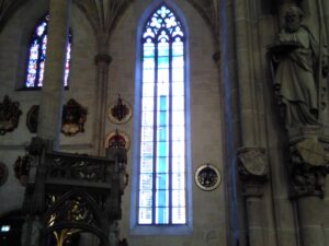 Gotische Fenster und historische Kunstwerke im Seitenschiff des Ulmer Münsters