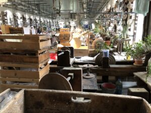 Werkhalle einer böhmischen Glasmanufaktur mit Holzkisten und Exponaten