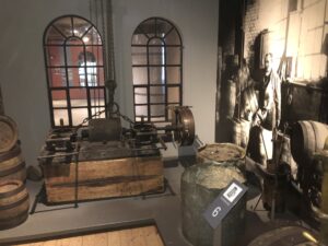 Blick in eine alte Brauereiszene mit Fässern und Arbeitsgerät