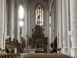 Goldener Altaraufbau vor bunt verglastem gotischen Maßwerkfenster
