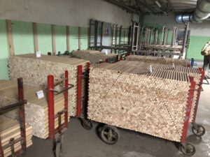 Auf Wagen gestapelte, runde Holzrohlinge in der Werkhalle