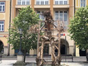 Vogelscheuchenartige Holzfigur vor historischer Häuserzeile