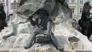 Steinskulptur mit erhobenem Arm vor Felskulisse