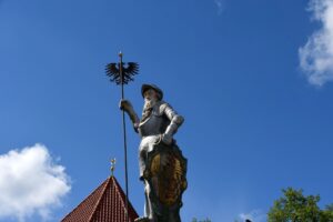 Eine Figur auf einem Dachfirst vor blauem Himmel