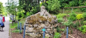 Bemooste Liegefigur, eingefasst von einer niedrigen Mauer