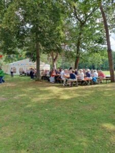 Tischgruppen unter Bäumen vor dem Festzelt
