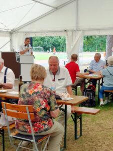 Gäste am Tisch, im Hintergrund der Sportplatz